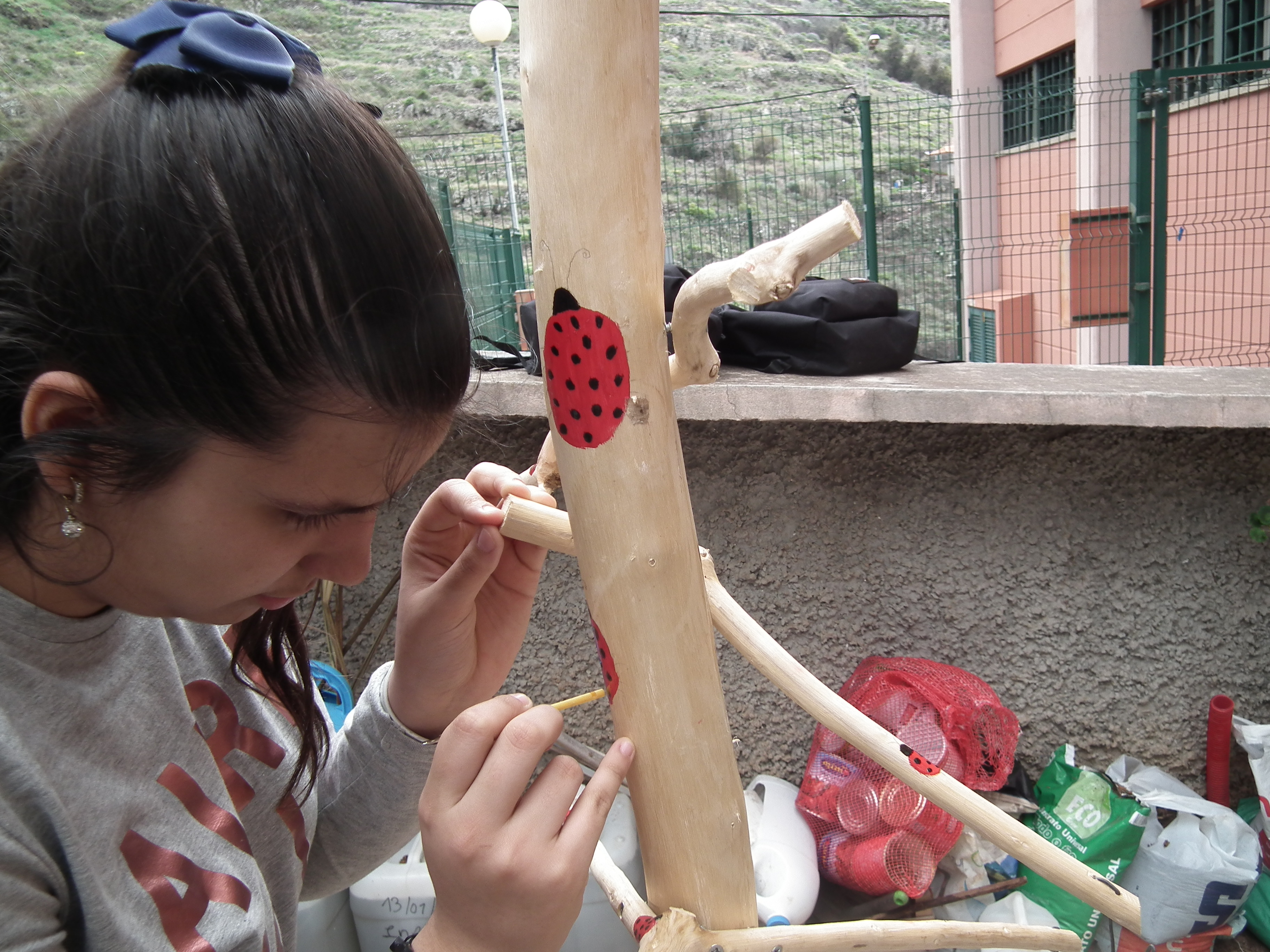 Uma das alunas pintando uma joaninha na estrutura de madeira.